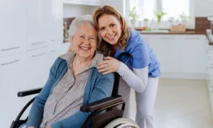 Smiling caregiver with an elderly woman in a wheelchair, representing social and care-giving volunteer work in Malta.
